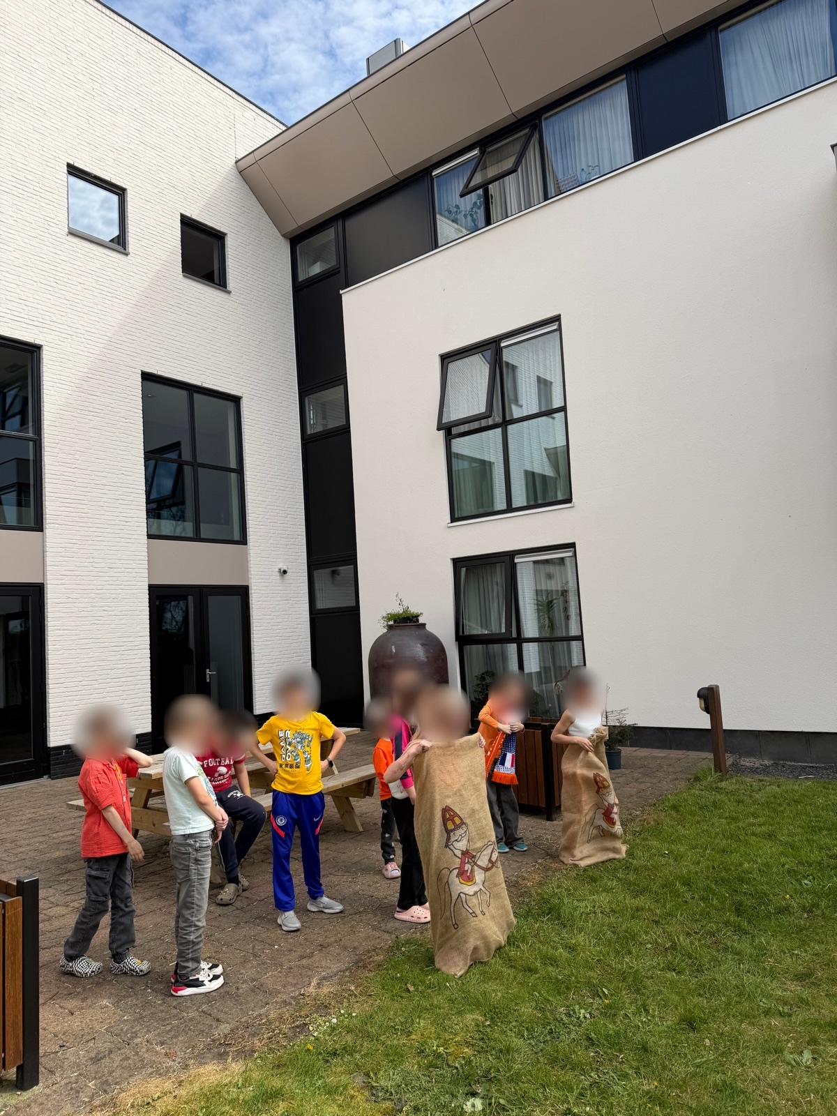 Kinderen doen mee aan zaklopen op de binnenplaats van de opvanglocatie (gezichten vervaagd)