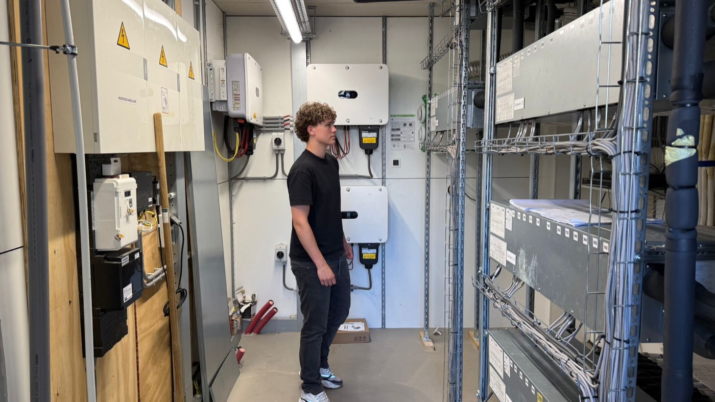 Stagiair Thomas bekijkt de installaties in de technische ruimte van de opvanglocatie